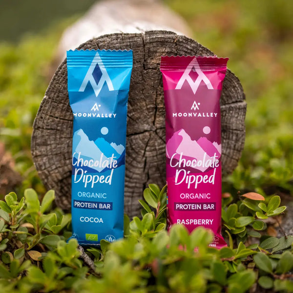 Moonvalleys ekologiska proteinbars med kakao och hallon, fotograferade i naturlig utomhusmiljö.
