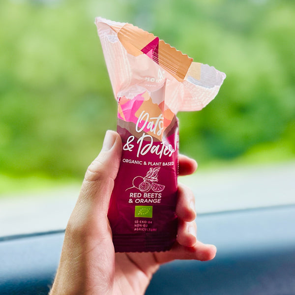 Hand som håller öppnad Moonvalley energibar med smak av rödbeta och apelsin.